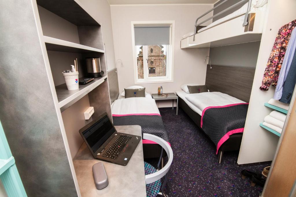 Compact hotel room with a fitted bed, shelving and a moulded shower unit
