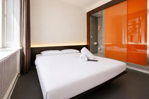 Small uniform hotel room with a bed and a compact shower unit against one wall