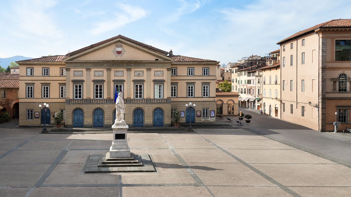 Nineteenth-century hotel front on a stone square beside a theatre facade