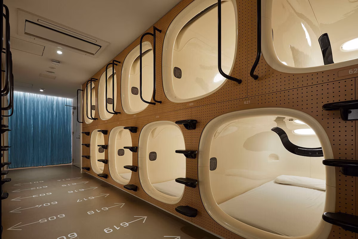 Rows of moulded sleeping units stacked in two tiers along a lit corridor